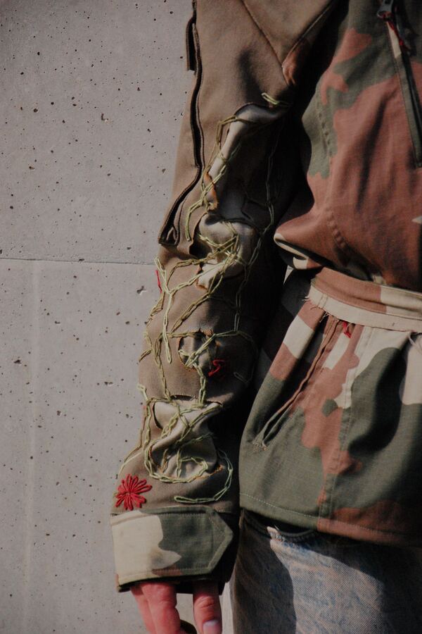 Sleeve detail: gathered, ruched fabric running the length of the arm, finished with a red embroidered flower.
