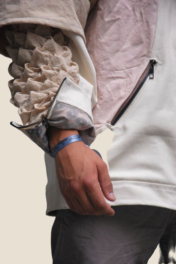 Sleeve detail: the same gathering worked in undyed cloth, beside a zipped pocket.